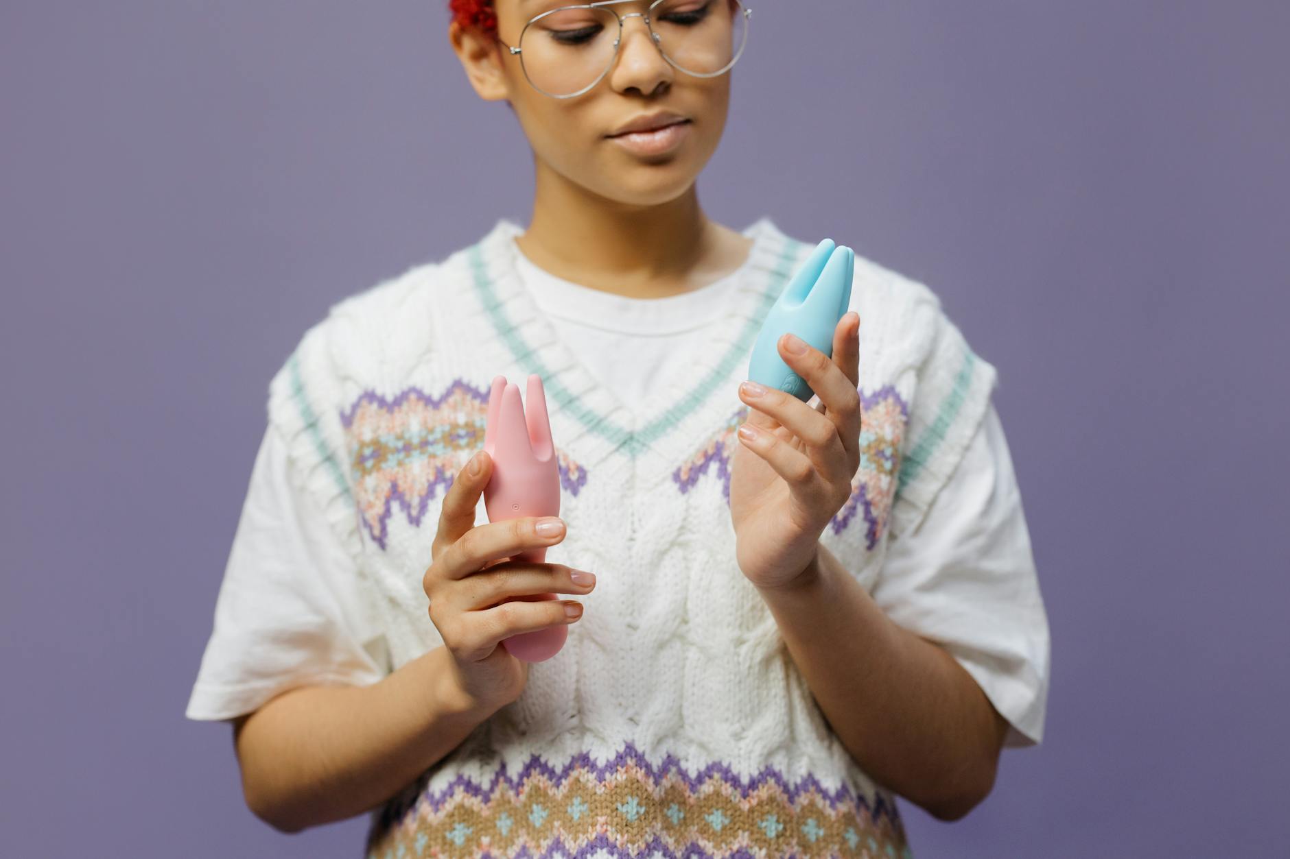 Woman holding lemon and pink clitoral vibrators in thoughtful repose