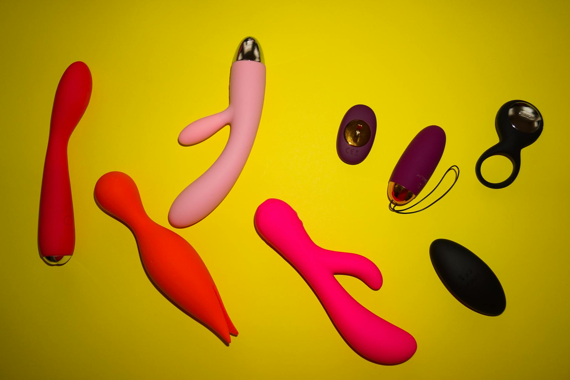 Yellow silicone vibrator surrounded by fruit on a yellow background