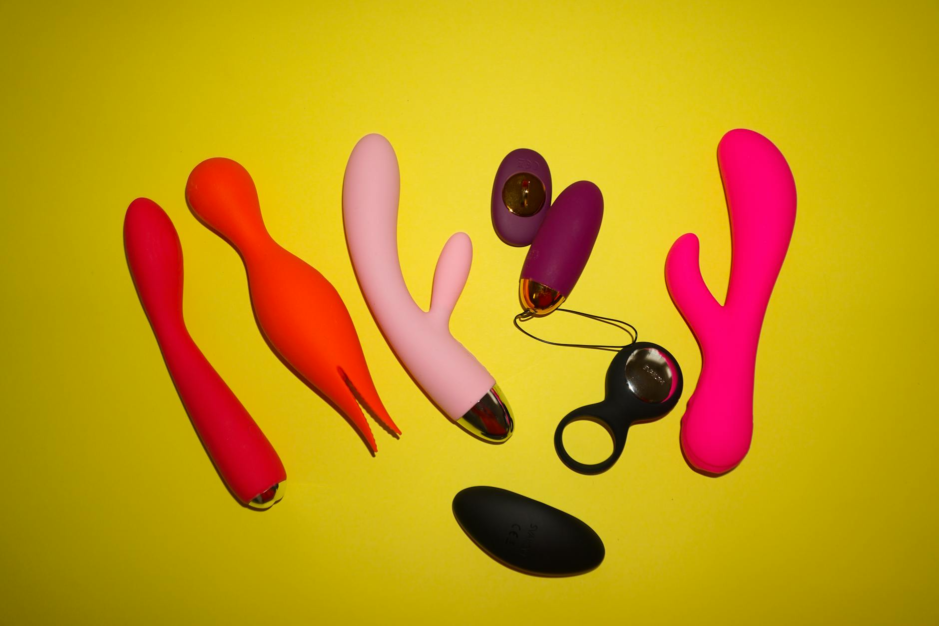 Colorful vibrators arranged on a bright background with flowers and citrus, representing seasonal pleasure and renewal